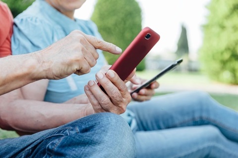 A photo of a couple using mobile phones on a bench